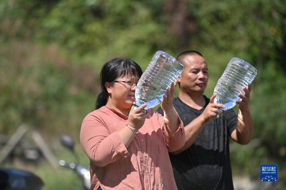 楊寧（左）在查看村民剛剛采集的水樣，為山泉水引水工程做準備（10月8日攝）。新華社記者 黃孝邦 攝